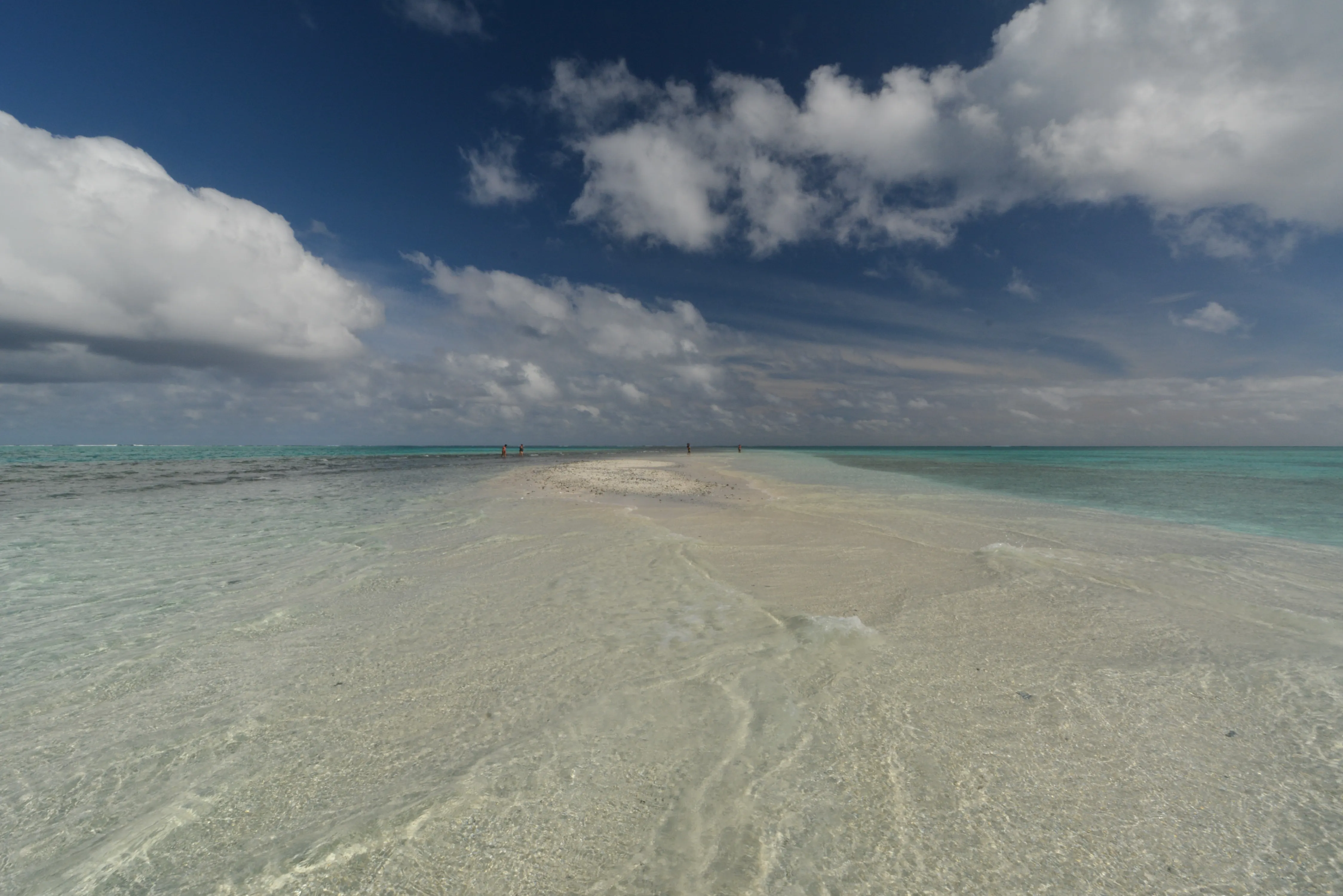 Vue aérienne du lagon turquoise de Polynésie, un motu bordé de sable blanc au loin